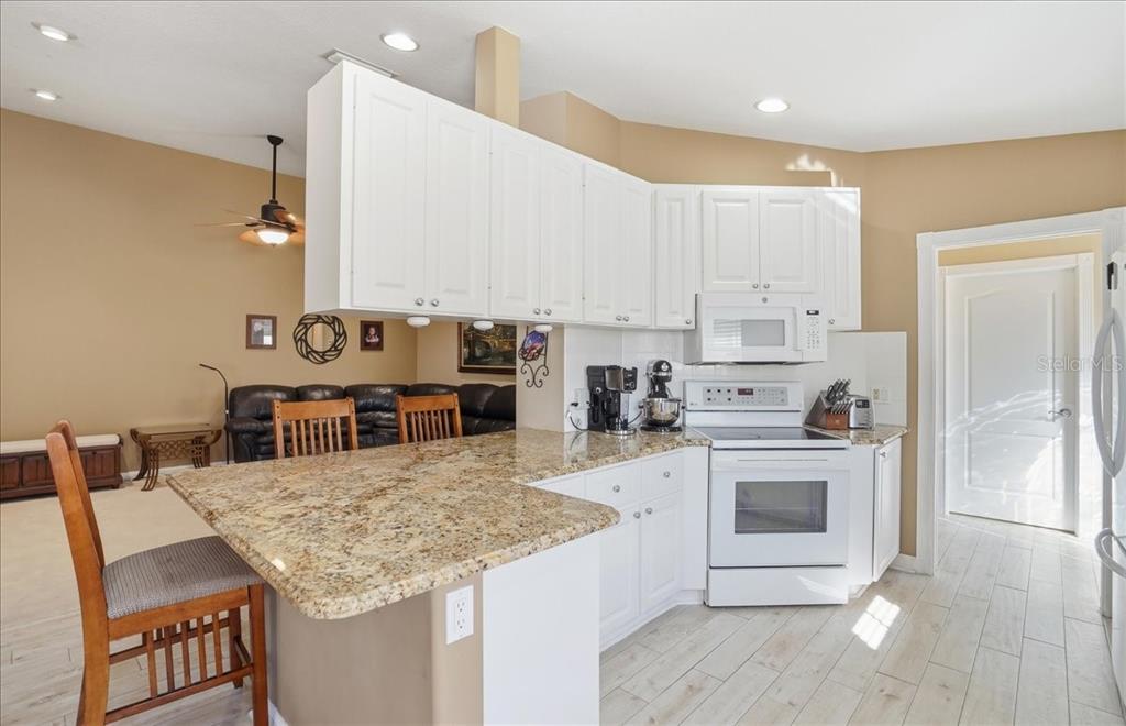 5546 Modena Place Sarasota, FL 34238 - Photo 8 of 67 a kitchen with stainless steel appliances kitchen island granite countertop a table chairs sink and cabinets