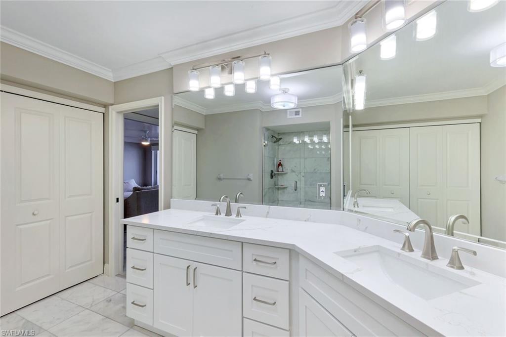 9103 Vanderbilt Drive, Unit 208 Naples, FL 34108 - Photo 10 of 23 a bathroom with double vanity and a mirror