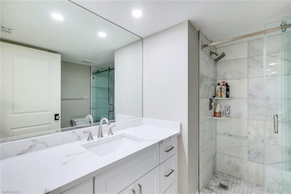 9103 Vanderbilt Drive, Unit 208 Naples, FL 34108 - Photo 13 of 23 a bathroom with a double vanity sink mirror and shower