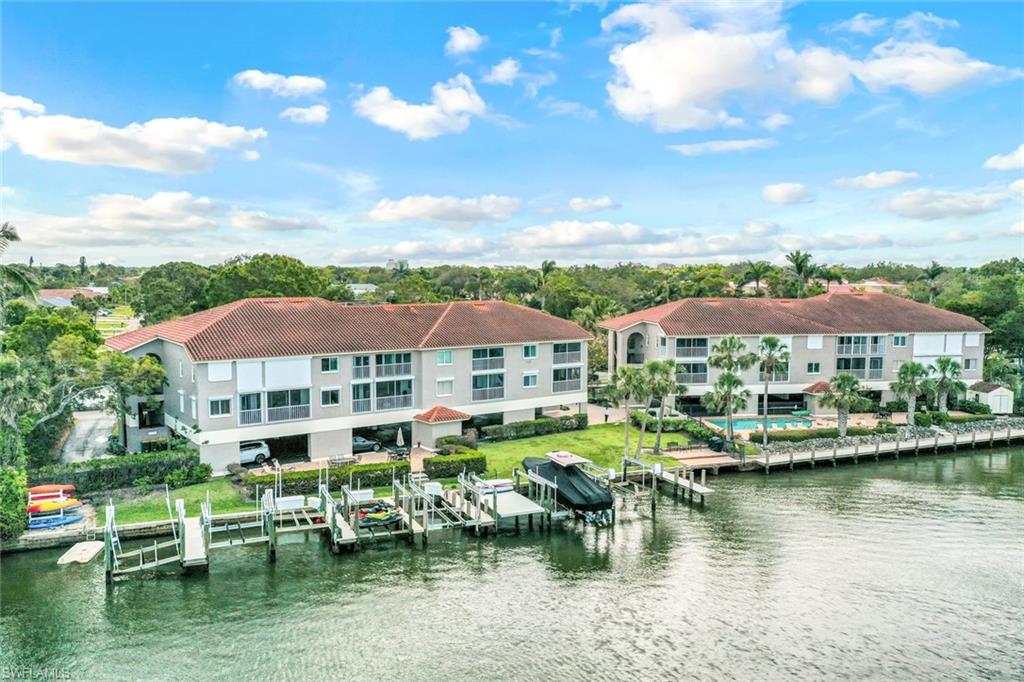 9103 Vanderbilt Drive, Unit 208 Naples, FL 34108 - Photo 18 of 23 a front view of a house with a garden and lake view