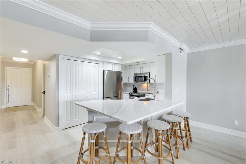 9103 Vanderbilt Drive, Unit 208 Naples, FL 34108 - Photo 5 of 23 a kitchen with stainless steel appliances a table and chairs in it