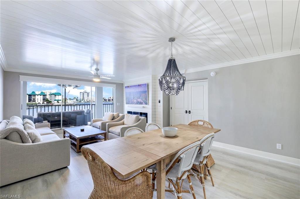 9103 Vanderbilt Drive, Unit 208 Naples, FL 34108 - Photo 6 of 23 a view of a dining room with furniture wooden floor and chandelier