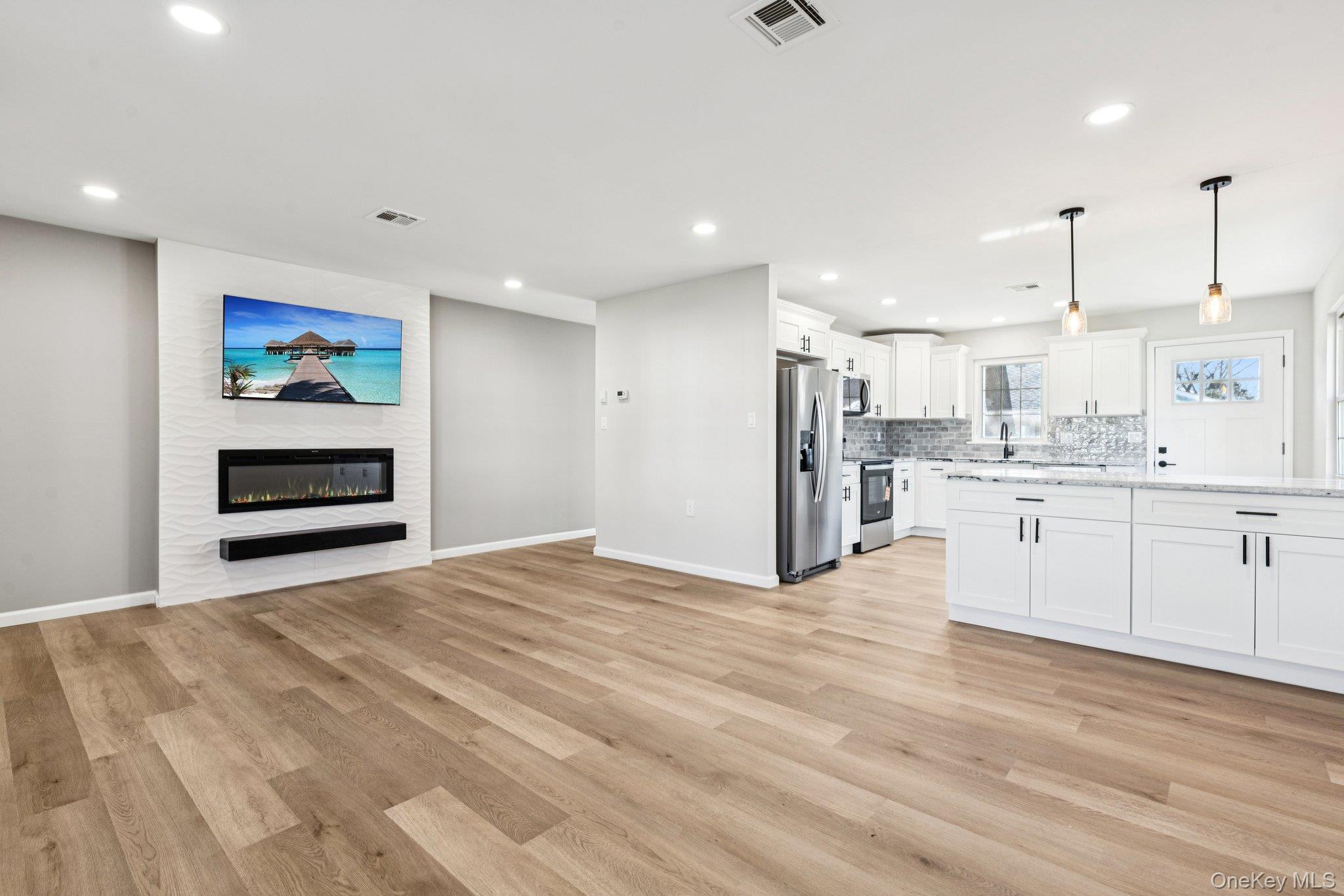195 Canterbury Drive Ridge, NY 11961 - Photo 9 of 26 a large white kitchen with kitchen island a sink stainless steel appliances and cabinets