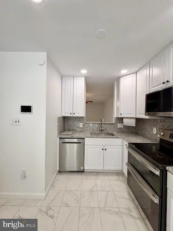 a large kitchen with granite countertop a stove a sink and a refrigerator