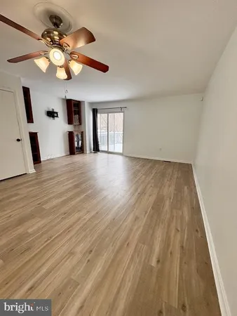 a view of an empty room with window and wooden floor