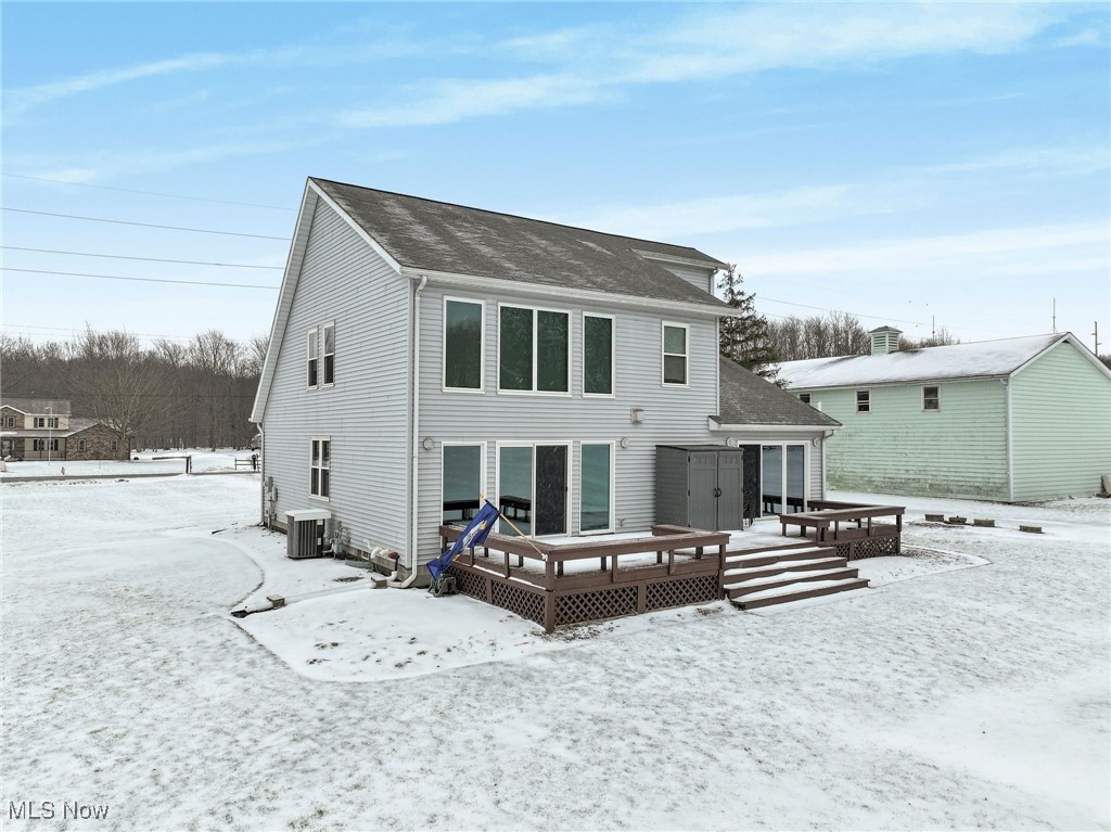 200 Bates Road Madison, OH 44057 - Photo 37 of 42 Snow covered rear of property featuring central AC unit, a deck, and a shingled roof