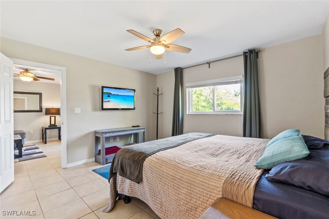 138 Cypress Way East, Unit 404 Naples, FL 34110 - Photo 22 of 32 a bedroom with a large bed and a chandelier