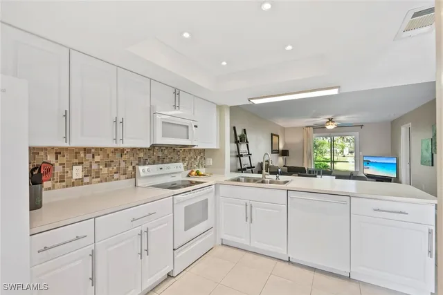a kitchen with white cabinets sink and stove