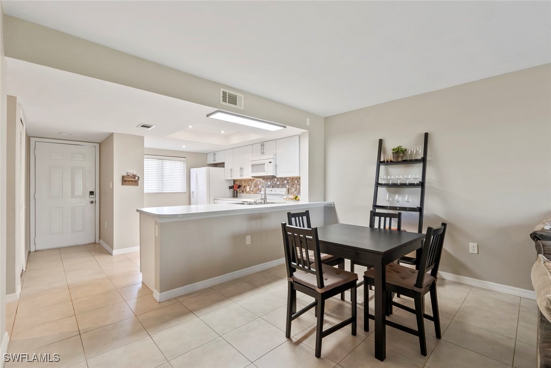 138 Cypress Way East, Unit 404 Naples, FL 34110 - Photo 10 of 32 a kitchen with a table and chairs in it