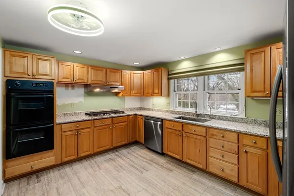 a kitchen with granite countertop a refrigerator sink and cabinets