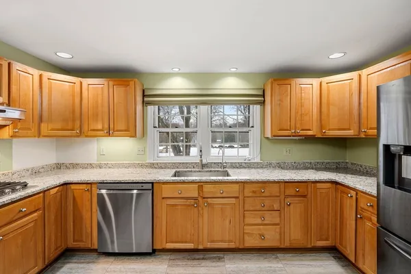 a kitchen with granite countertop wooden cabinets a sink a window and stainless steel appliances