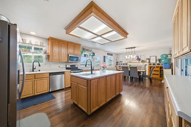 a kitchen with stainless steel appliances granite countertop wooden floors a stove a sink and a refrigerator