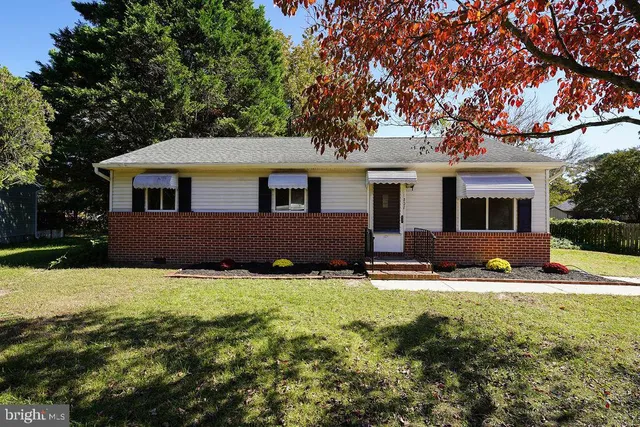 a front view of house with yard and trees in the background