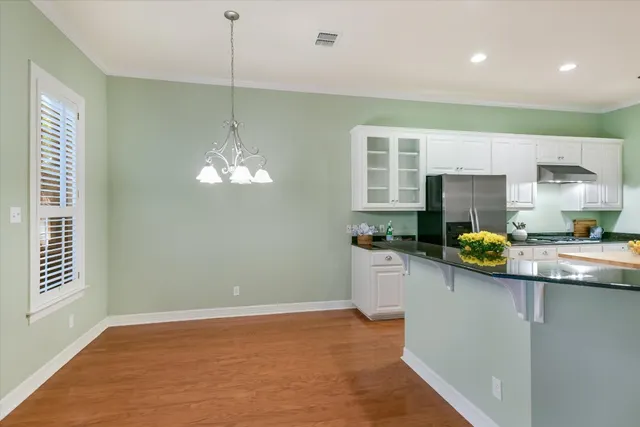 a kitchen with stainless steel appliances granite countertop a sink a stove a chimney a refrigerator and a window