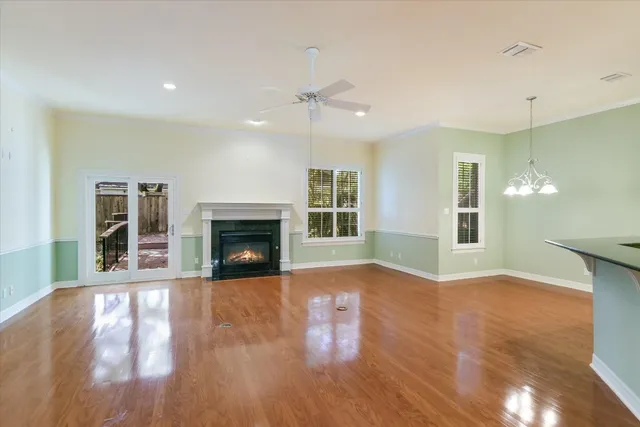 a view of an empty room with wooden floor fireplace and a window