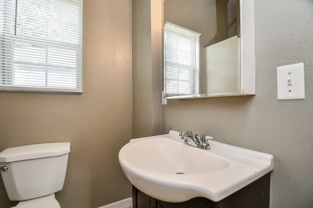 a bathroom with a sink a toilet and a window