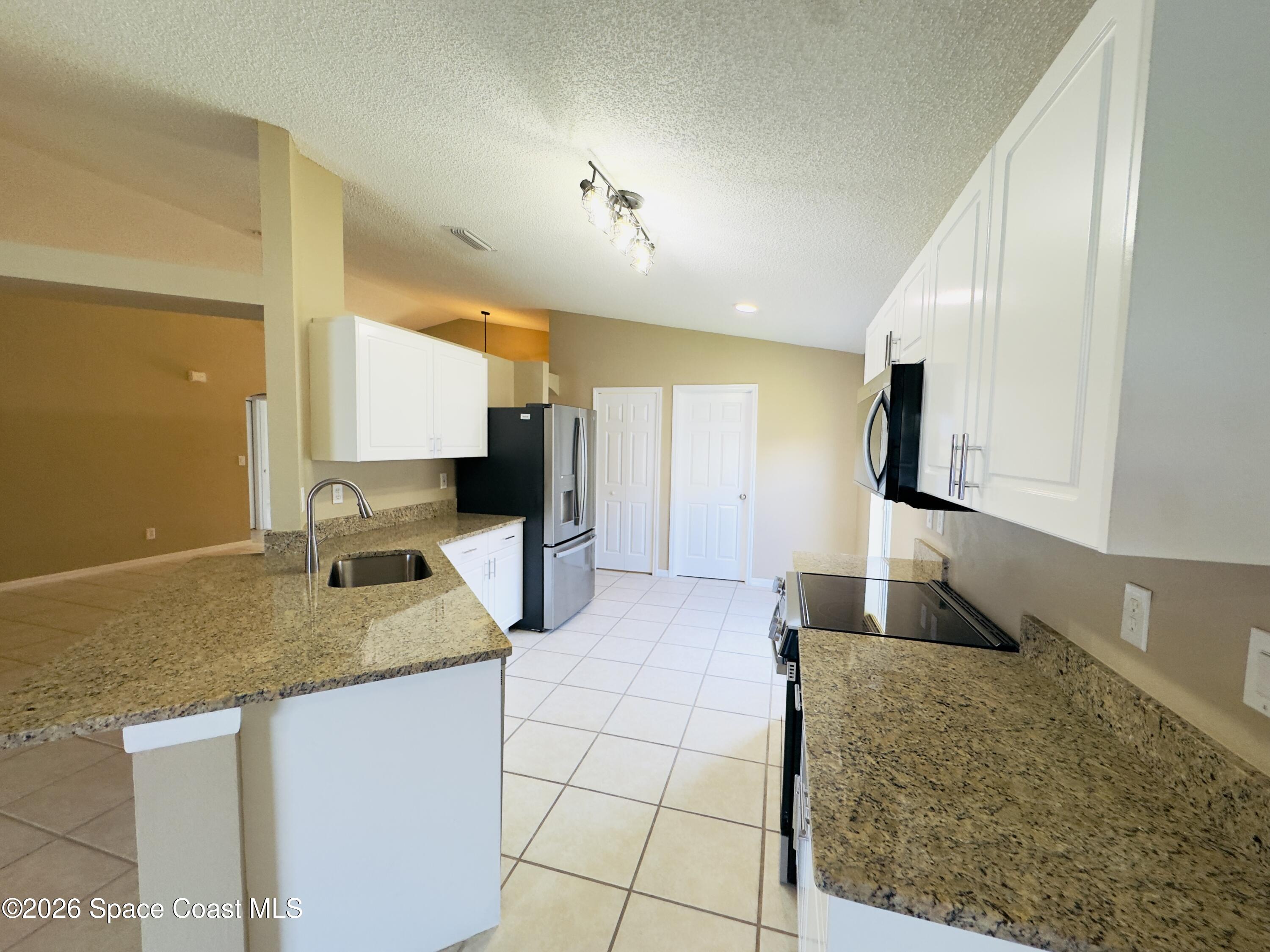 4691 Manchester Drive Rockledge, FL 32955 - Photo 2 of 4 a kitchen with granite countertop a sink a stove and cabinets