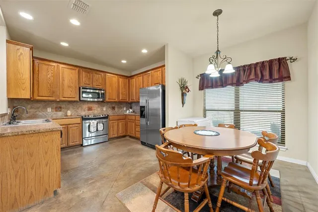 a kitchen with stainless steel appliances kitchen island granite countertop a sink a stove a table and chairs