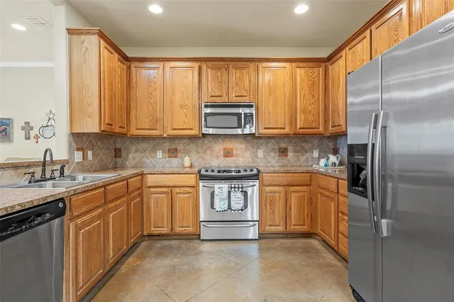 a kitchen with stainless steel appliances granite countertop a stove a sink dishwasher and a refrigerator