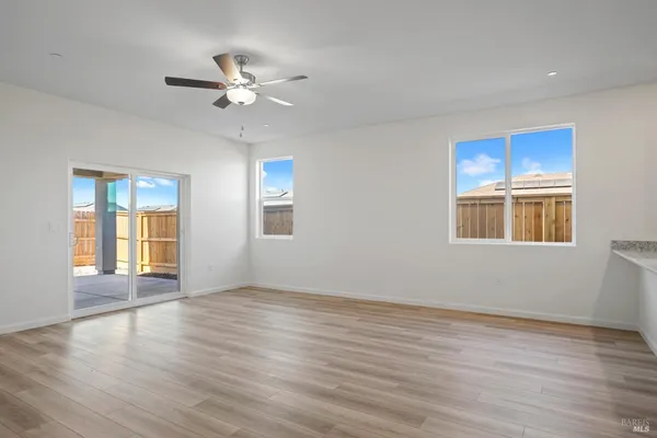 a view of an empty room with window and wooden floor