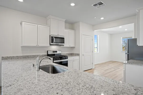 a kitchen with granite countertop a stove a sink and a refrigerator