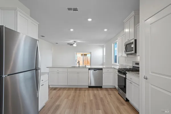 a kitchen with stainless steel appliances granite countertop a refrigerator a stove top oven a sink and dishwasher
