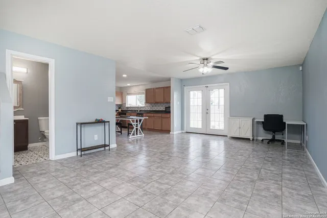 a view of an empty room with a window and a kitchen