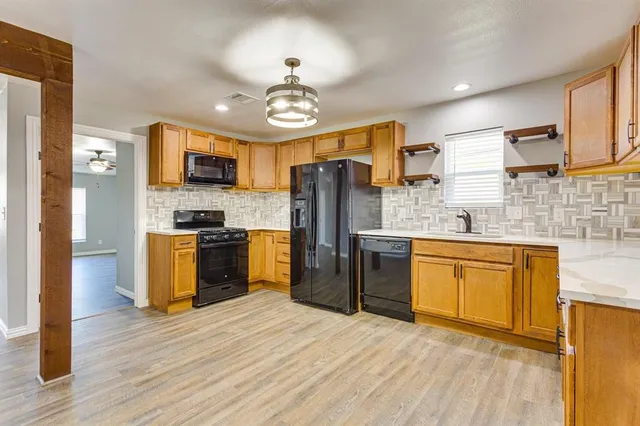 a kitchen with stainless steel appliances granite countertop a refrigerator a stove top oven a sink dishwasher and wooden floor