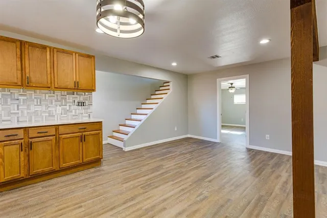 an empty room with wooden floor cabinet and windows