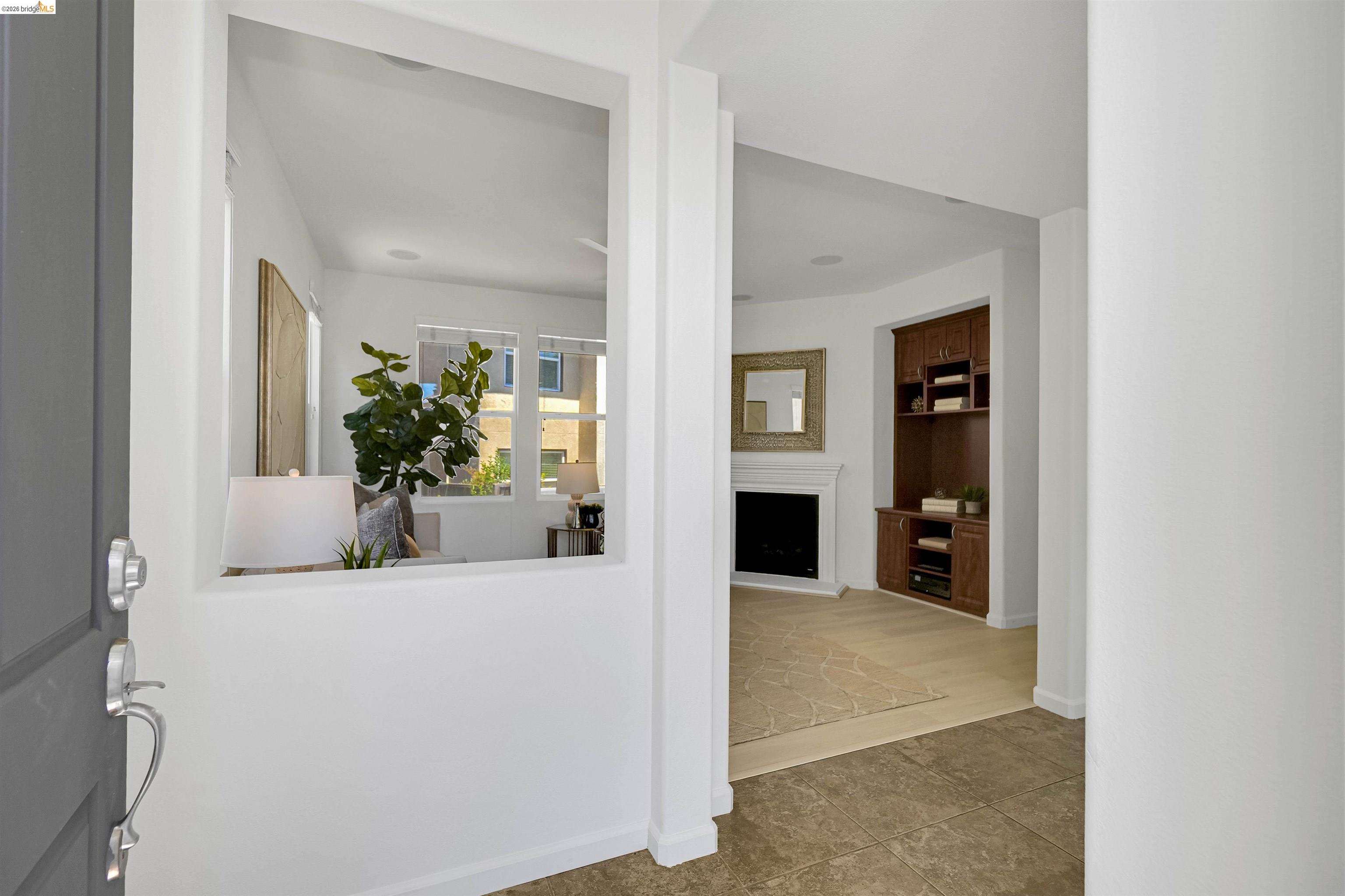 449 Constantine Court San Ramon, CA 94583 - Photo 11 of 63 Entryway featuring large format floor tiles, a built-in media center with wood-finish cabinetry, a fireplace with a white mantel, and a decorative interior window