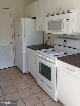 a kitchen with white cabinets and white appliances