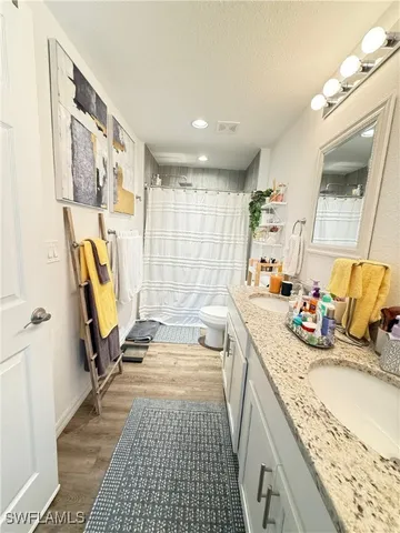 a bathroom with a granite countertop sink a mirror and a shower