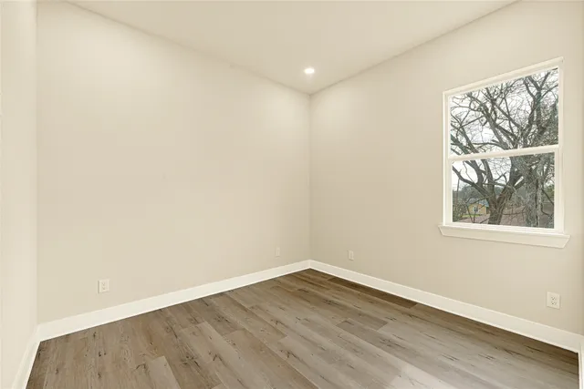 an empty room with wooden floor and a window