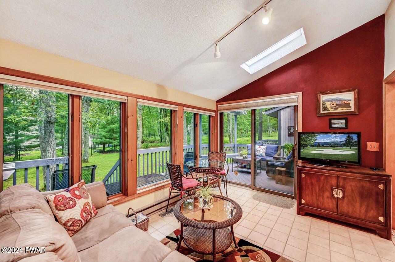 141 Maple Ridge Drive Hawley, PA 18428 - Photo 10 of 84 a living room with furniture a flat screen tv and floor to ceiling windows