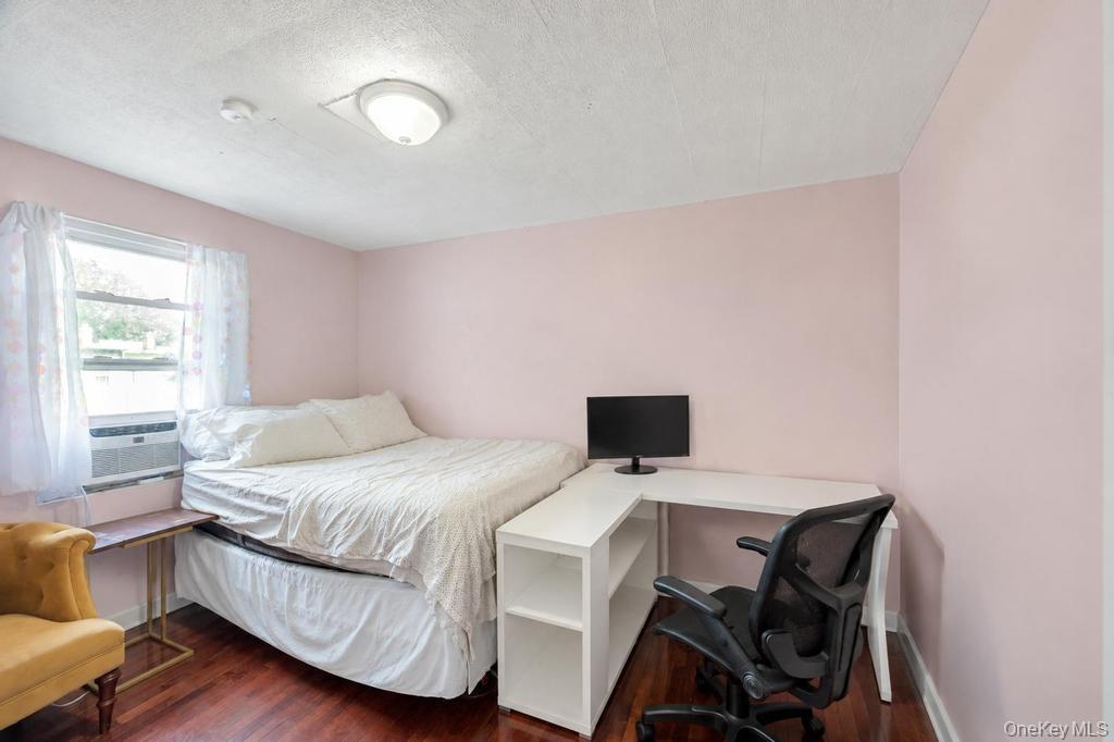 89-13 84th Street Queens, NY 11421 - Photo 25 of 34 Bedroom featuring a window-mounted air conditioning unit, wood-finish flooring, and a flush-mount ceiling light fixture