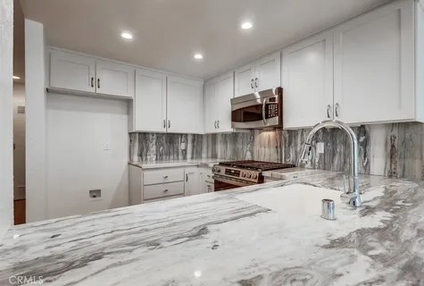 a kitchen with granite countertop a stove a sink and a microwave