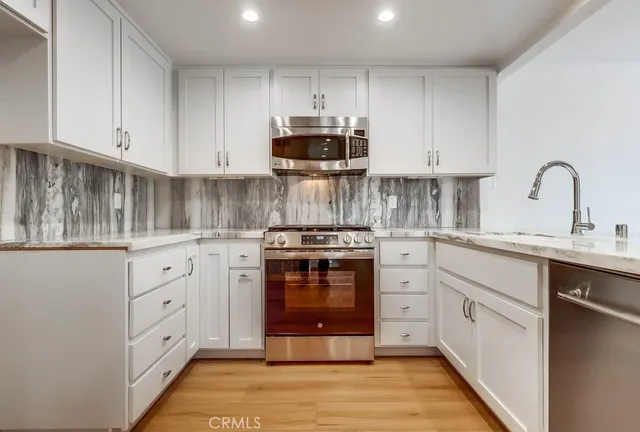 a kitchen with white cabinets and appliances