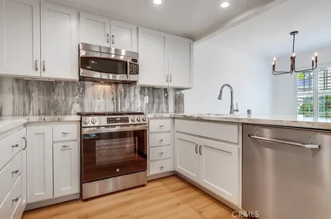 a kitchen with stainless steel appliances granite countertop a stove a sink and a microwave