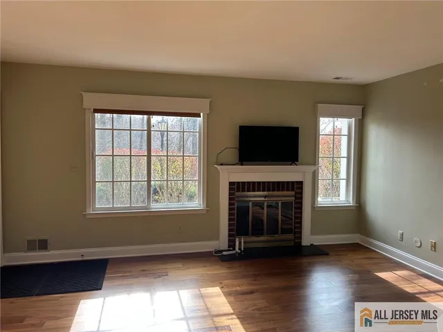 an empty room with windows a fireplace and wooden floor