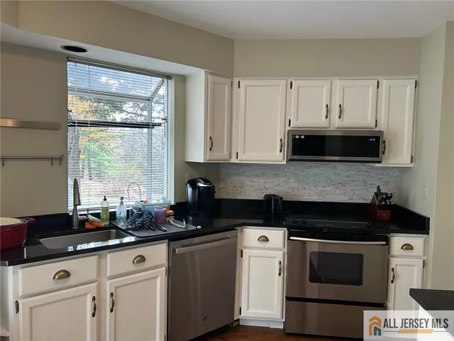 a kitchen with granite countertop white cabinets and black appliances