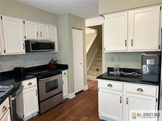 a kitchen with granite countertop a stove a sink and a microwave
