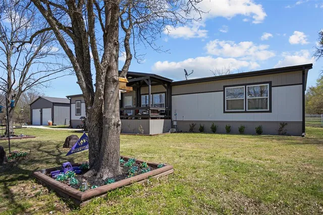 a house view with a sitting space fire pit and trees in front of it