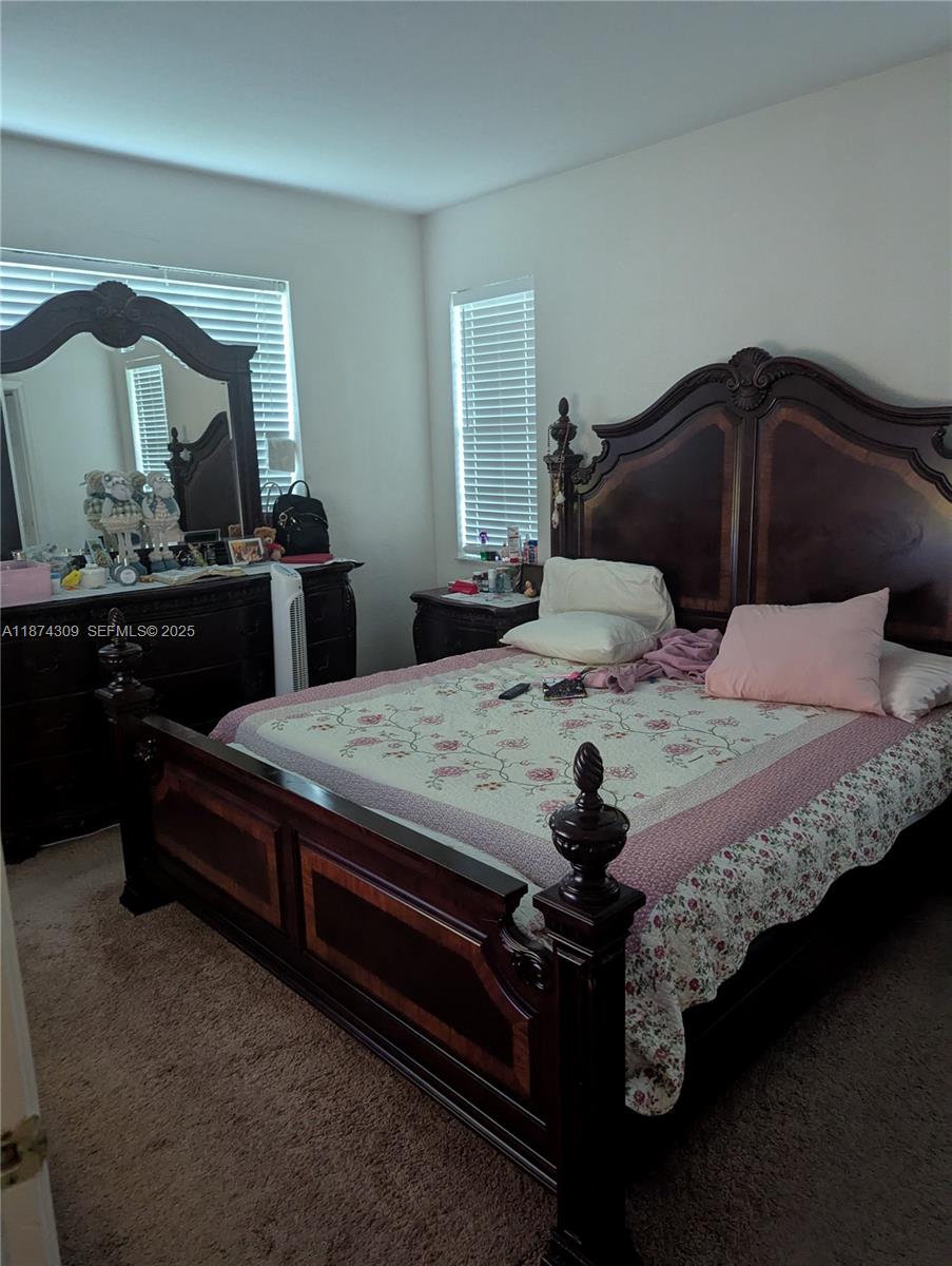 8496 Southwest 29th Street, Unit 104 Miramar, FL 33025 - Photo 11 of 19 a bedroom with a bed and a mirror on dresser