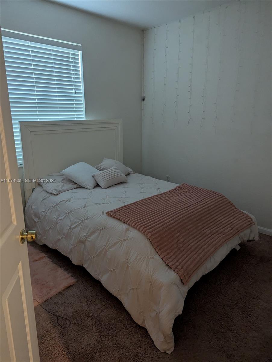8496 Southwest 29th Street, Unit 104 Miramar, FL 33025 - Photo 16 of 19 a bed sitting in a bedroom next to a window