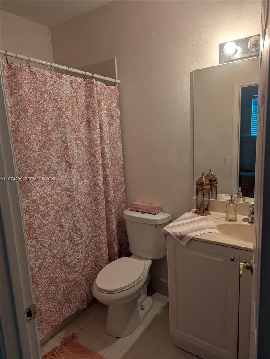 8496 Southwest 29th Street, Unit 104 Miramar, FL 33025 - Photo 17 of 19 a bathroom with a sink a toilet a mirror and shower curtain