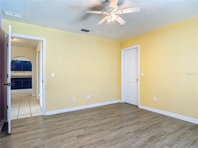 an empty room with windows and a ceiling fan