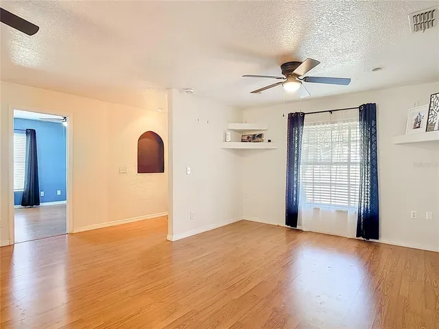 a view of empty room with wooden floor and ceiling fan