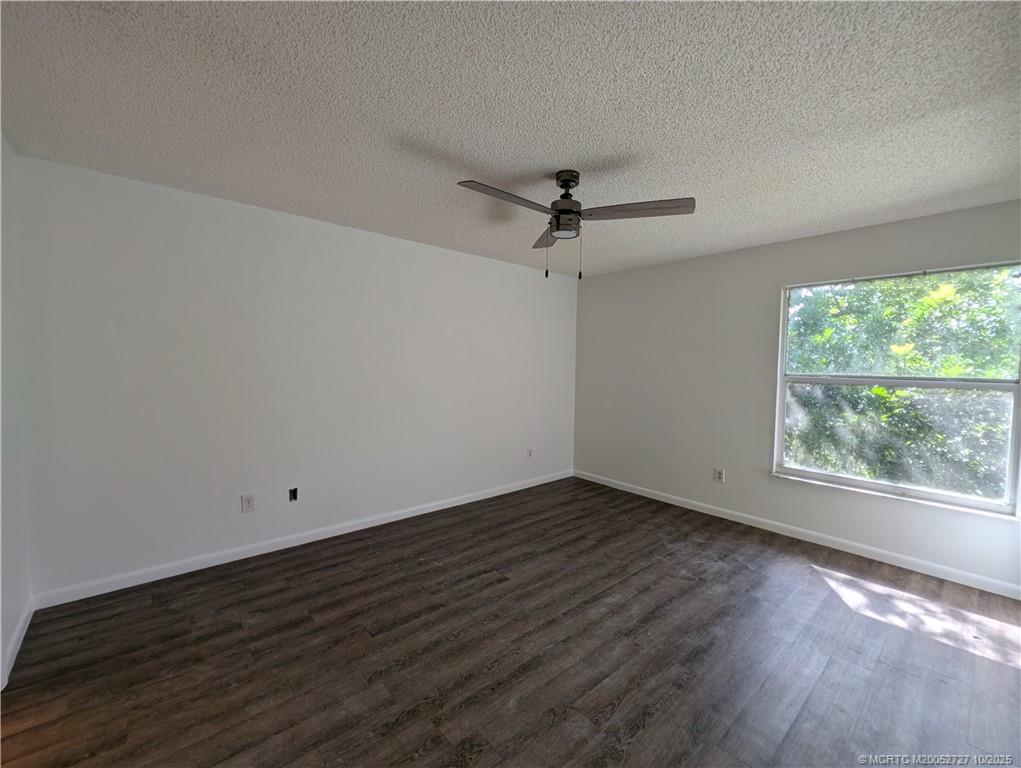 8291 Southeast Croft Circle, Unit M8 Hobe Sound, FL 33455 - Photo 13 of 22 an empty room with wooden floor fan and windows