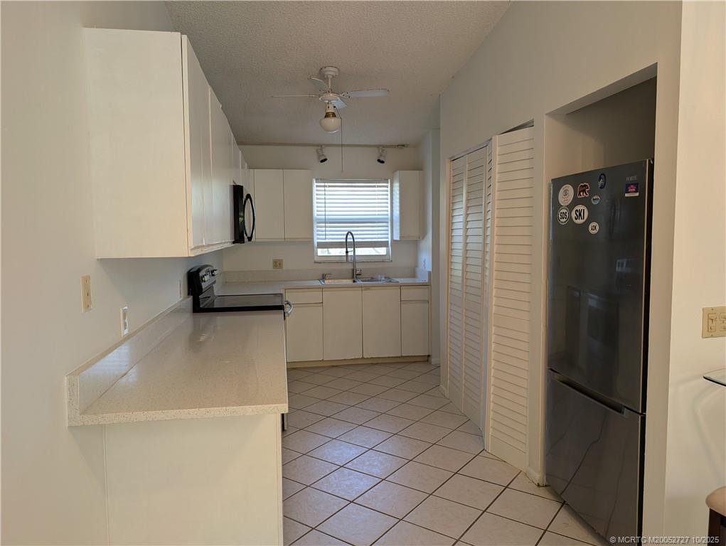 8291 Southeast Croft Circle, Unit M8 Hobe Sound, FL 33455 - Photo 8 of 22 a kitchen with a sink a refrigerator and cabinets