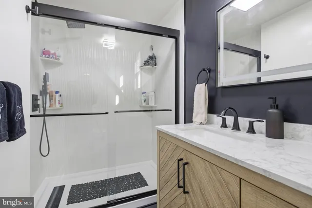 a bathroom with a granite countertop sink a mirror and shower